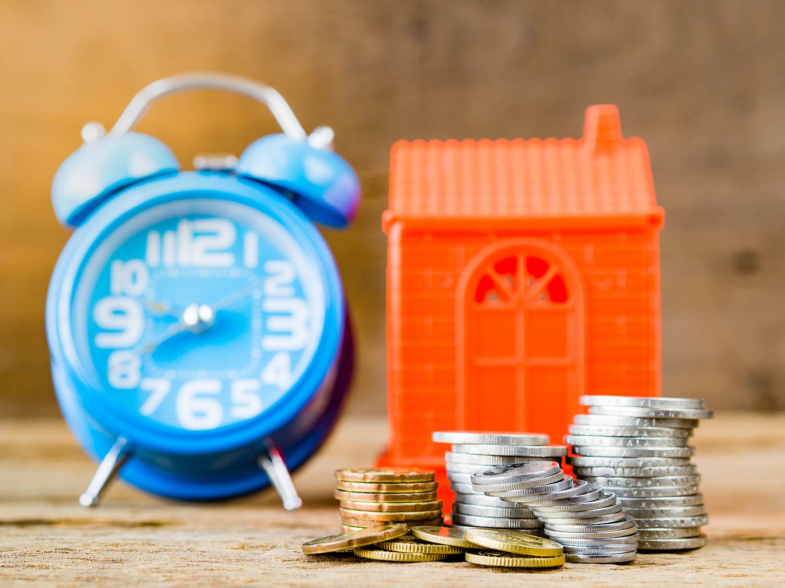 A clock and a house with change stacked in front