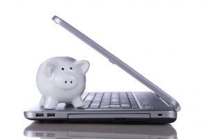 Piggybank over a modern laptop, the cost of technology and information (isolated on white)