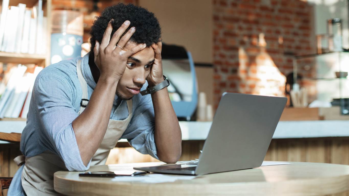 a man sits in front of his computer looking frustrated