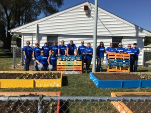 Group picture with team standing behind the four, colorful garden beds.