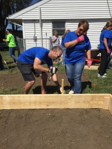 Corey Cates and Rebecca Price pound a stake that will keep the raised bed in place.